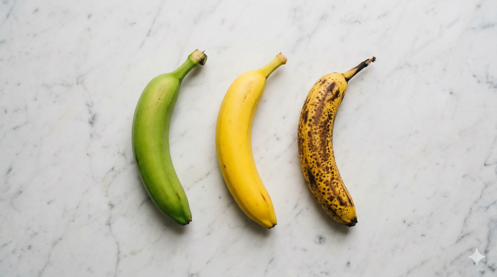 Drie bananen in verschillende rijpheid: groen, geel en bruin