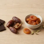 Gezond snoep alternatieven: pure chocolade, medjoul dadels en noten op houten plank